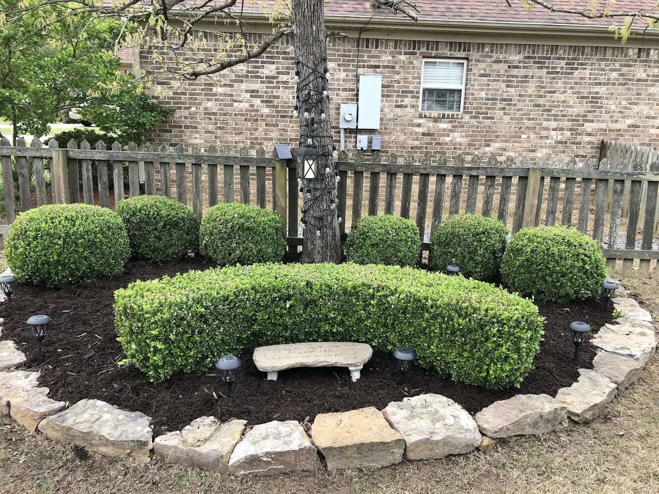 Round mulch bed with raised stone border and manicured grass