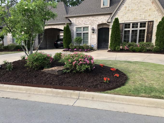 Dark mulch beds with flowering shrubs along home foundation