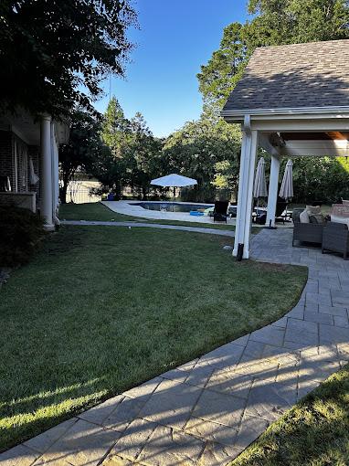 Backyard stone patio with pergola and mature landscaping